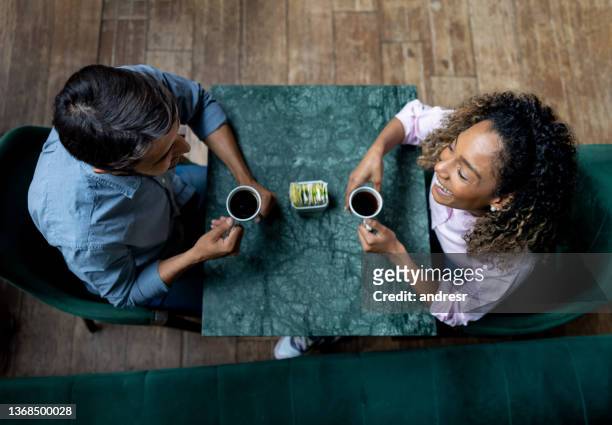 happy couple smiling while having a cup of coffee at a cafe - coffee happy stockfoto's en -beelden