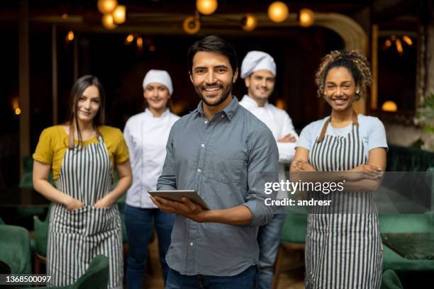 portrait of a business owner smiling with his staff at a restaurant - happy cooks restaurant stock pictures, royalty-free photos & images