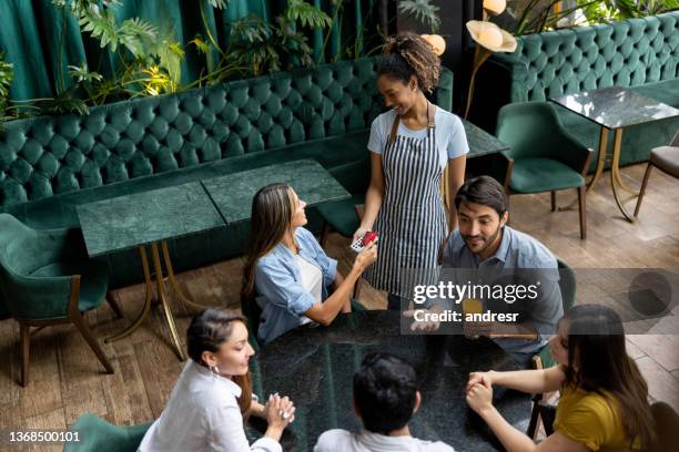 woman paying by card at a restaurant - paying for dinner imagens e fotografias de stock