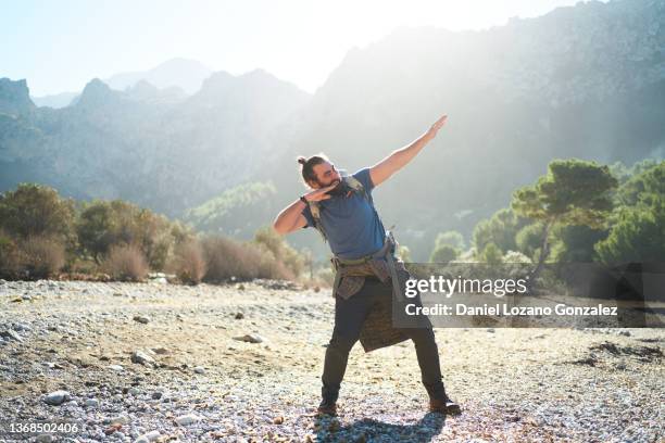 smiling traveling man showing dab gesture in highlands - showing off fotografías e imágenes de stock