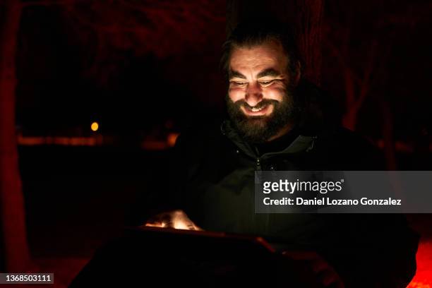 cheerful male browsing tablet in dark park - dark humor stock pictures, royalty-free photos & images