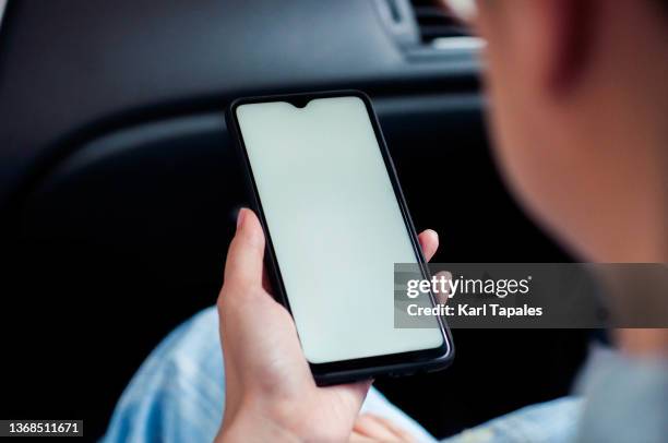 a southeast asian woman is using a smart phone with white screen in the car - auto display stock-fotos und bilder