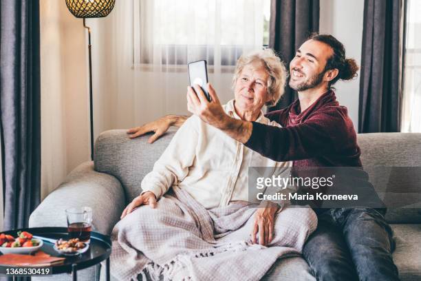 adult son making selfie with senior mom at home. - grandmother son stock pictures, royalty-free photos & images
