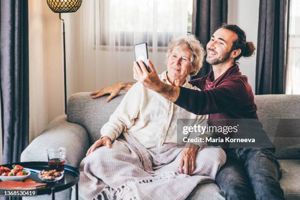 adult son making selfie with senior mom at home. - moder maria bildbanksfoton och bilder