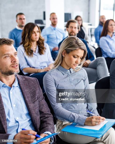 large group of entrepreneurs taking notes on a seminar in board room. - men and women in a large group listening stock pictures, royalty-free photos & images