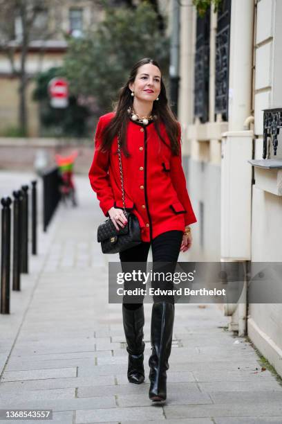 Alba Garavito Torre wears large pearls pendant earrings, a large gold chain and white pearls necklace, a red wool vintage jacket with black profiles...