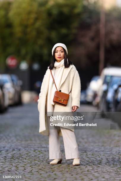 May Berthelot wears a white cashmere beanie from Eric Bompard, a matching white cashmere scarf from Eric Bompard, a white latte wool pullover, a...