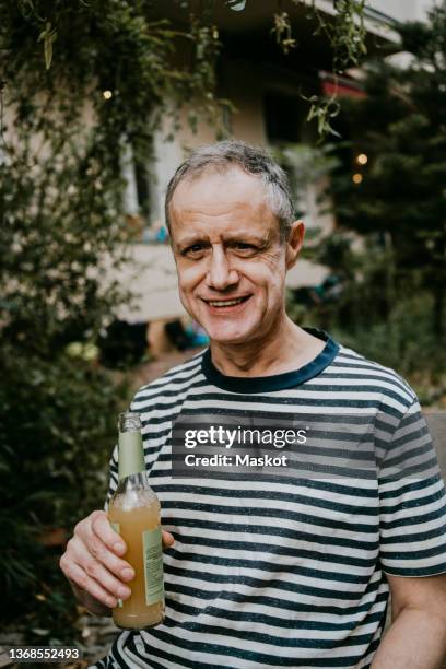 portrait of smiling mature man with beer bottle - bierflaschen stock-fotos und bilder