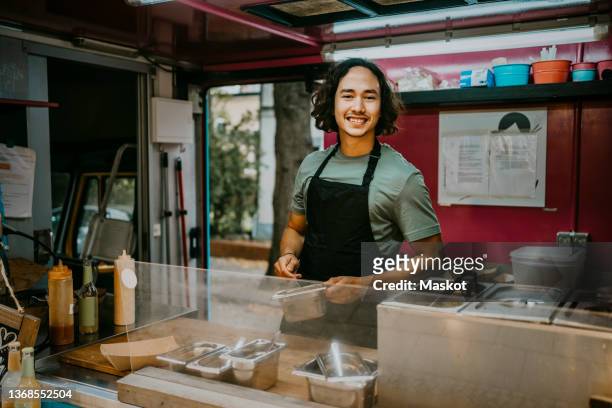 smiling male chef preparing food while working in food truck - food stall stockfoto's en -beelden