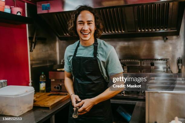 happy young male owner wearing apron in concession stand - tongs stock-fotos und bilder