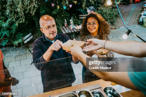 smiling male and female customer taking food container from concession stand - food truck stock pictures, royalty-free photos & images