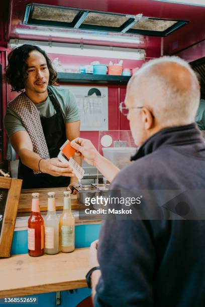 senior male customer paying with credit card to food truck owner - food truck payments stock pictures, royalty-free photos & images