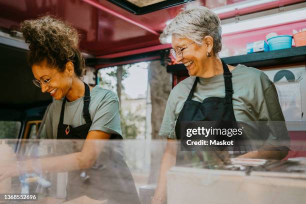 smiling female food truck owners preparing food together - gastronom stock-fotos und bilder