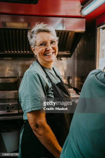 portrait of senior female owner in apron working in food truck - old truck stock-fotos und bilder