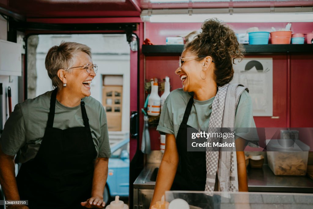 Female owner and coworker laughing in food truck kitchen