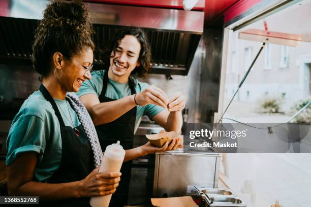 happy small business owners preparing food together in container - gastronom stock-fotos und bilder