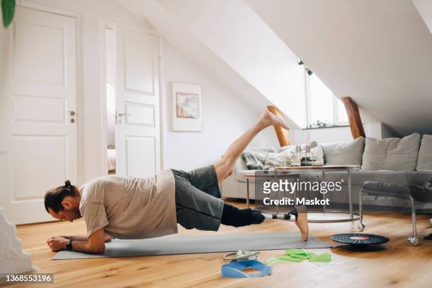 Active man with physical disability exercising in living room at home