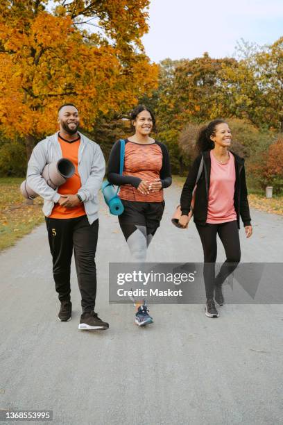 male and female friends walking together in park - yoga group stock pictures, royalty-free photos & images