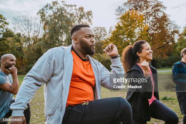 multiracial male and female friends exercising in park - fit man stockfoto's en -beelden