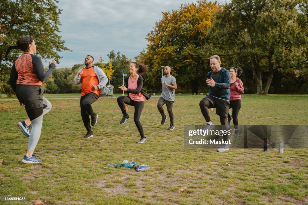 Female instructor teaching running exercise to men and women in park