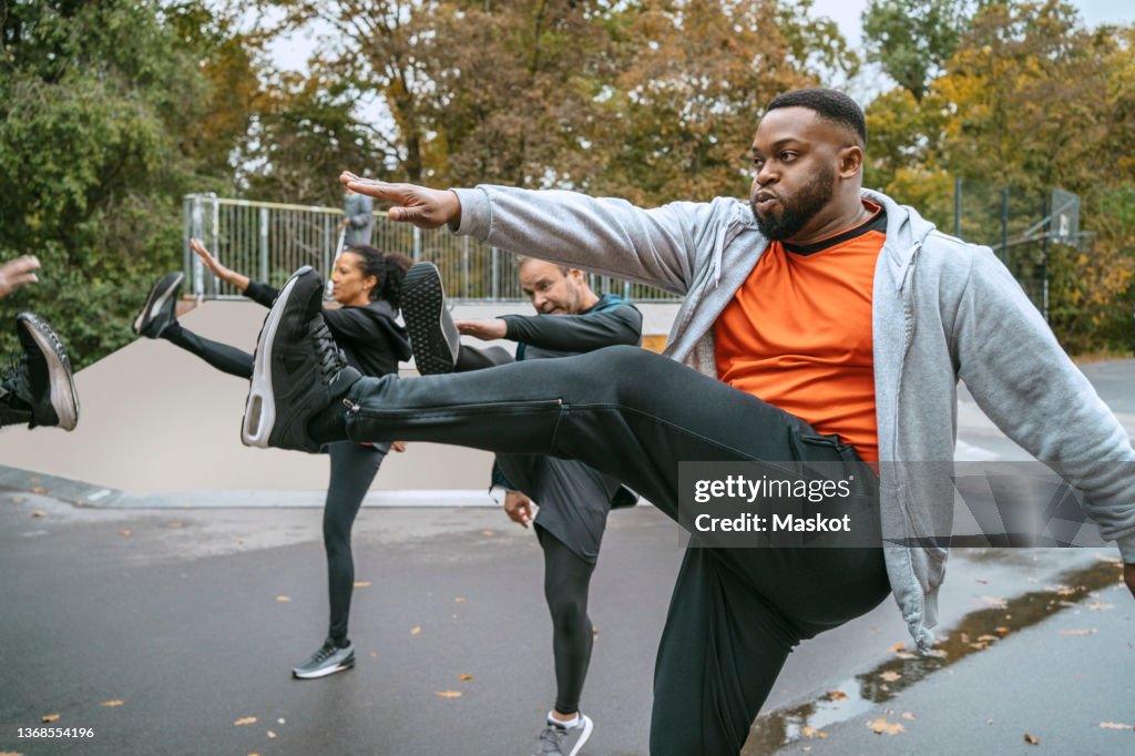 Multiracial male and female friends doing warm up exercise in park