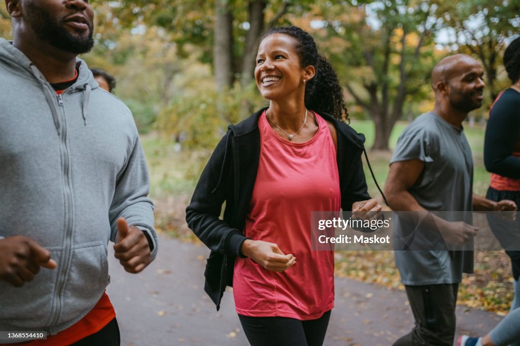 Happy woman talking with male friend while jogging in park