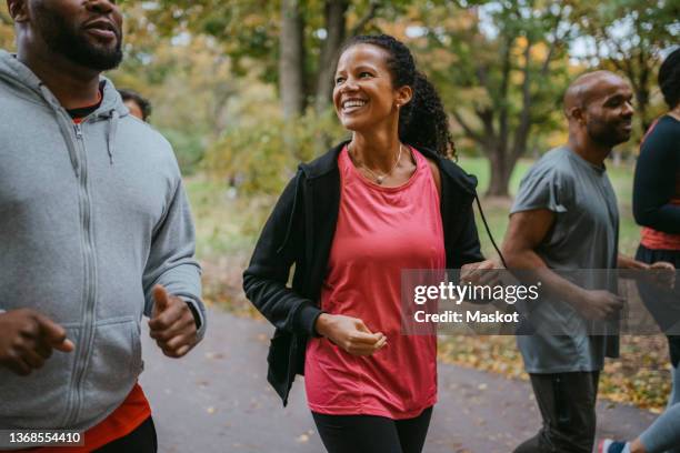 happy woman talking with male friend while jogging in park - 50 54 years outdoors stock pictures, royalty-free photos & images