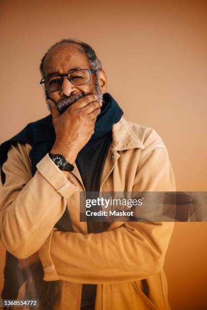 elderly man winking eye over brown background - winking eye stock pictures, royalty-free photos & images