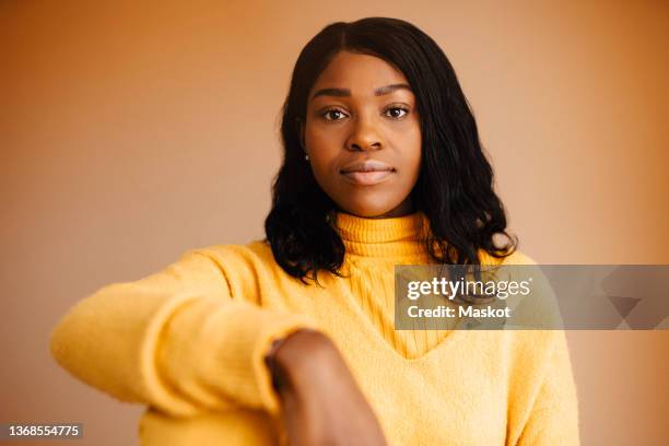 portrait of confident woman against brown background - formelles portrait stock-fotos und bilder