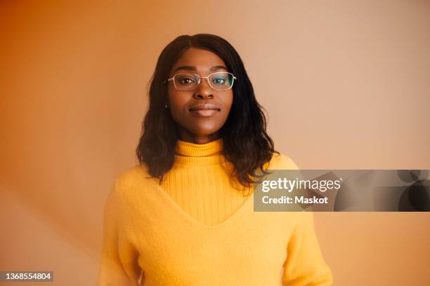 portrait of woman wearing eyeglasses against brown background - one woman only stock pictures, royalty-free photos & images