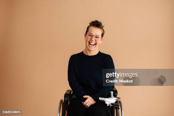 cheerful disabled woman looking away over brown background - brauner hintergrund stock-fotos und bilder