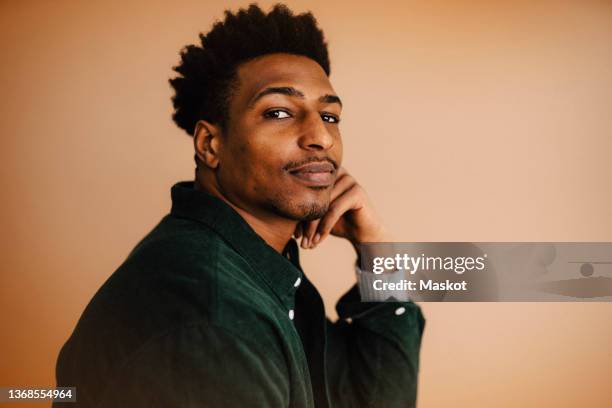 portrait of young man by brown background in studio - portret man stock pictures, royalty-free photos & images