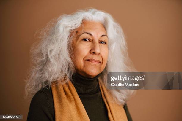 portrait of elderly woman with white hair against brown background - portrait woman stock pictures, royalty-free photos & images