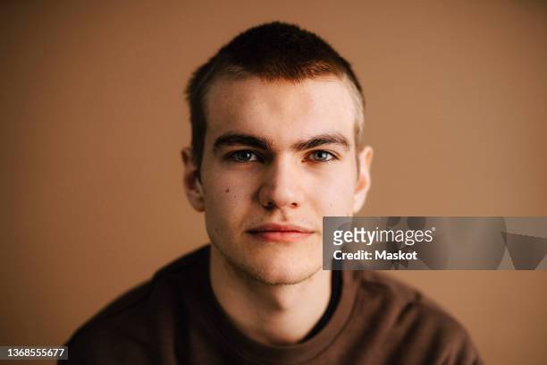 portrait of young man with gray eyes against brown background - brauner hintergrund stock-fotos und bilder