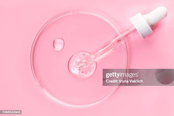 close-up pipette with face serum or essential oil with oxygen aqua bubbles and petryi dish on pastel pink color background. - petri dish stock-fotos und bilder