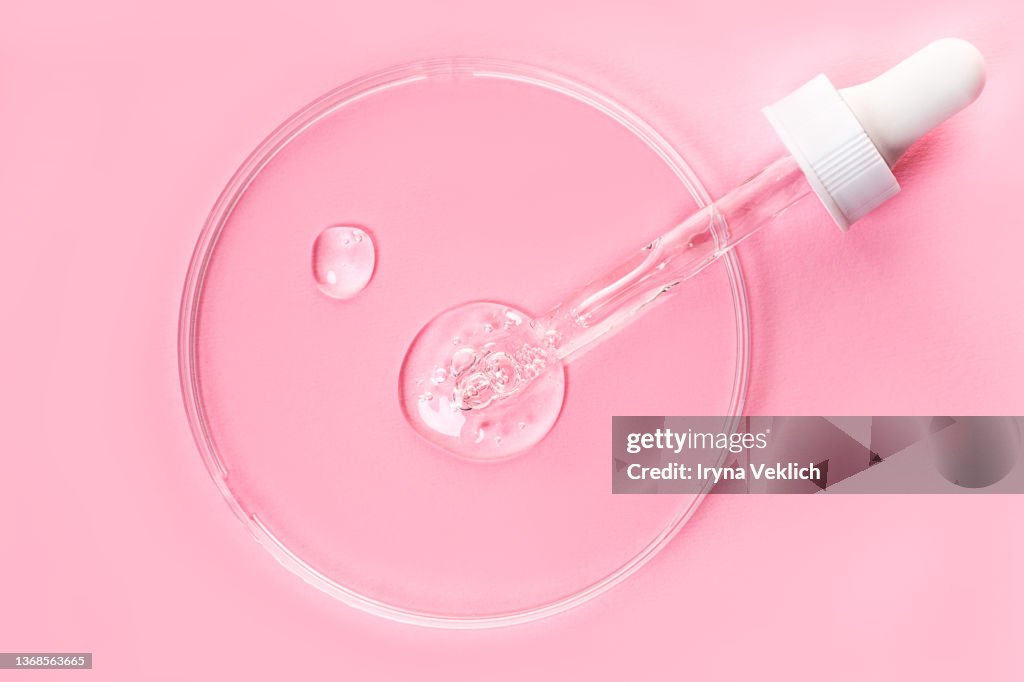 Close-up pipette with Face Serum or Essential Oil with Oxygen Aqua Bubbles and Petryi Dish on pastel pink color background.