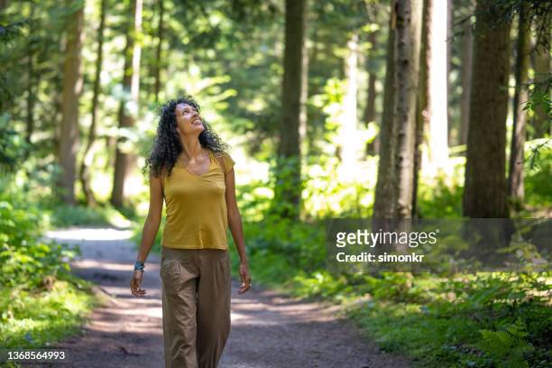 mature woman walking in forest - forest walking front stock pictures, royalty-free photos & images