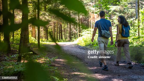 rear view of mature couple walking on dirt track in forest - slovenia hiking stock pictures, royalty-free photos & images