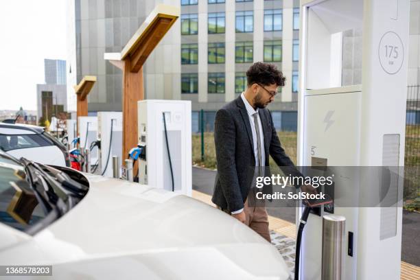 putting my electric vehicle on charge - elektroauto tanken stockfoto's en -beelden