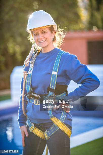 安全ハーネスを置く作業の準備ができている女性労働者 - harness ストックフォトと画像
