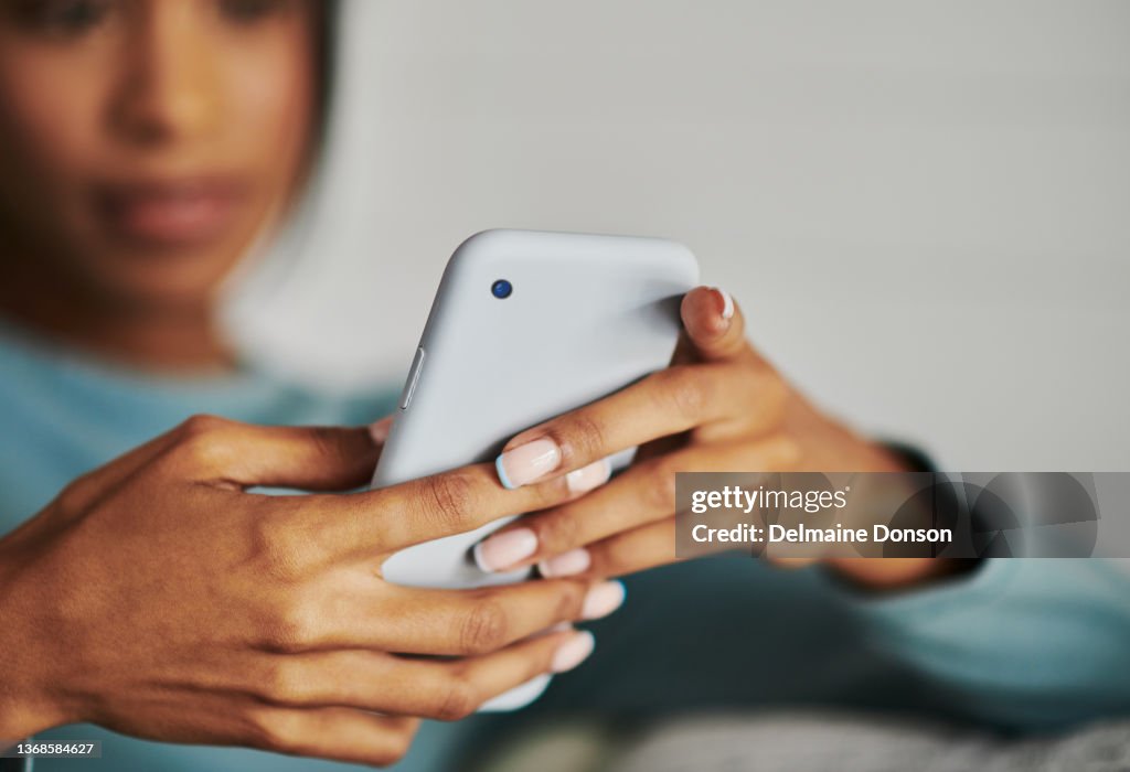 Shot of a young woman using a phone at home