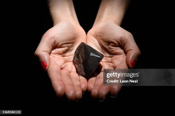 Member of the Sotheby's auction house team holds the "Enigma" black diamond on February 04, 2022 in London, England. The 55-sided, 555-carat 'Enigma'...