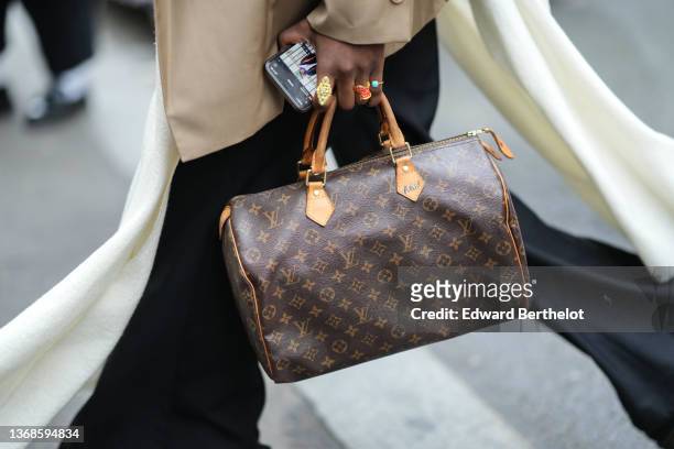 Guest wears a beige blazer jacket, black flared pants, a white long scarf, a brown LV monogram print pattern Speedy handbag from Louis Vuitton, ring,...