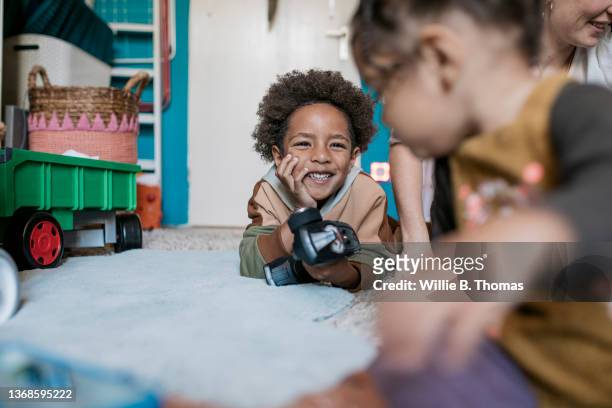 young boy smiling while playing with family - remote controlled car fotografías e imágenes de stock