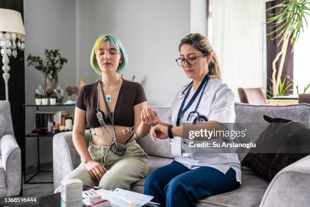 junge frau mit herzerkrankung wird mit holter verfolgt und betreuer besuchen sie zu hause - herzerkrankung stock-fotos und bilder