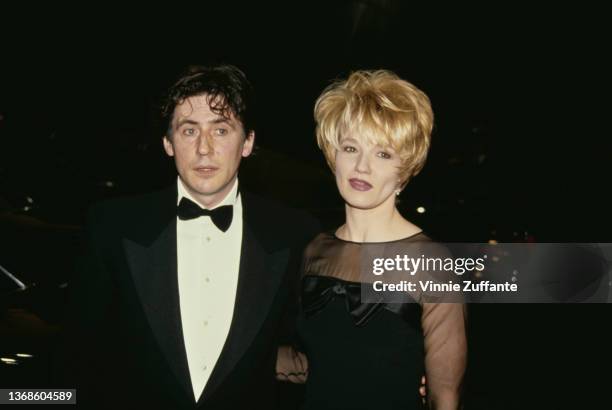 Irish actor Gabriel Byrne, wearing a tuxedo and bow tie, and his wife, American actress Ellen Barkin, wearing a black outfit with sheer sleeves,...