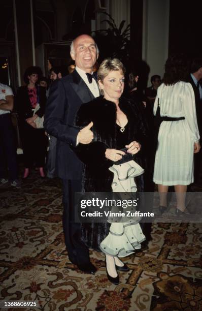 American actor Gavin MacLeod , wearing a tuxedo and bow tie, and his wife, Patti, wearing a black fur coat, attend an event, April 1985.