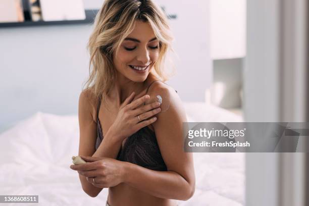 pretty blonde woman applying body lotion - skinny blonde pics stock pictures, royalty-free photos & images