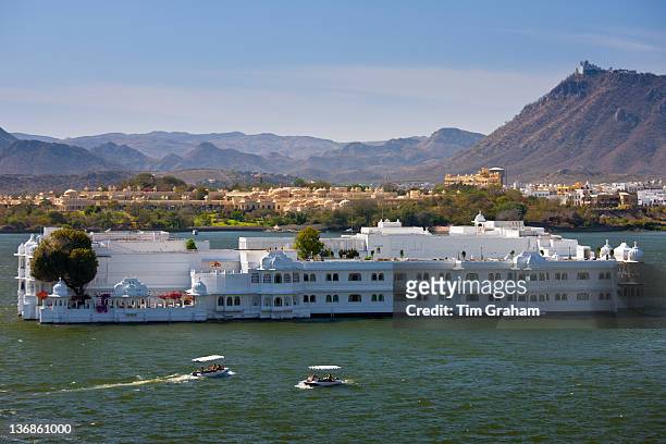 The Lake Palace Hotel, Jag Niwas, on island site on Lake Pichola with tourist boats arriving and leaving in Udaipur, Rajasthan, India