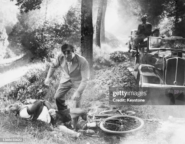 Man comes to the assistance of an rider who had come off his bicycle on a steep hill between Aubisque and Tourmalet while competing in the Tour de...